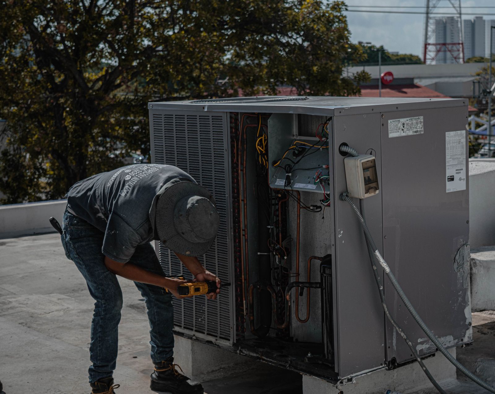 A technician servicing a rooftop air conditioning unit