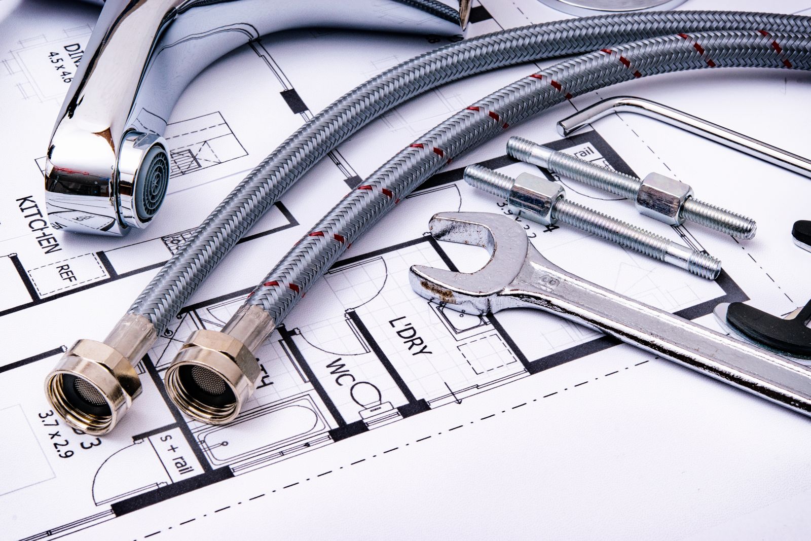Plumbing fittings and tools laid out on a set of plans