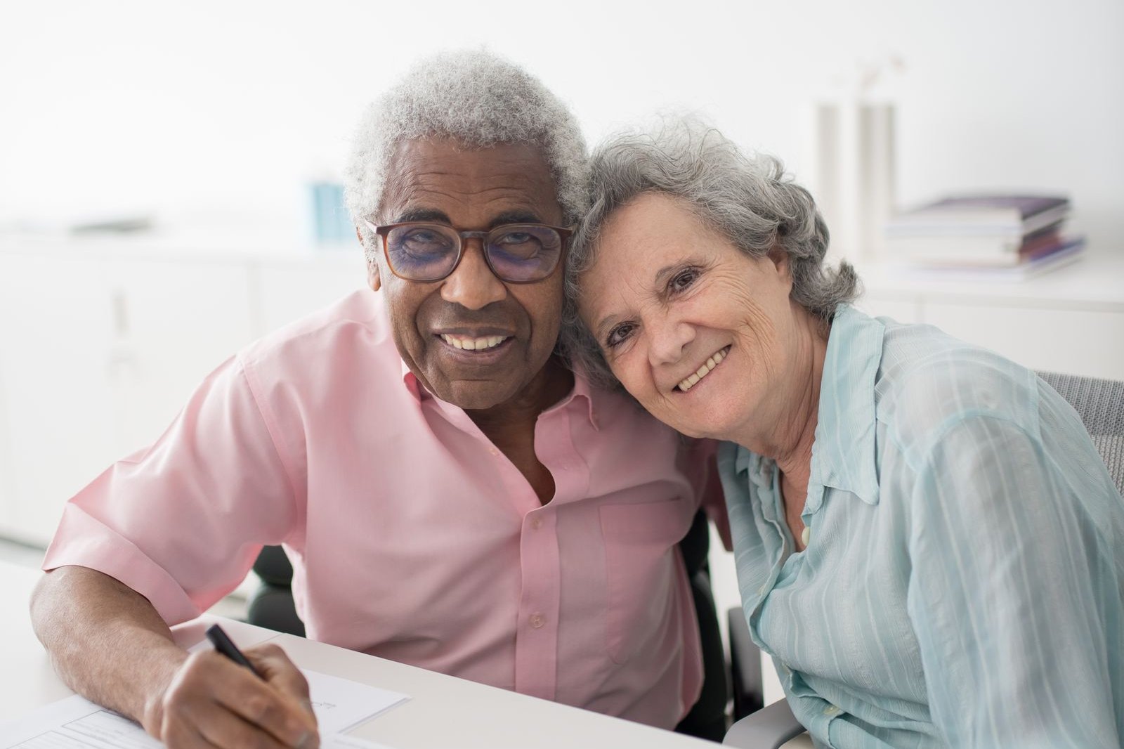 An older couple smiling as they sign paperwork