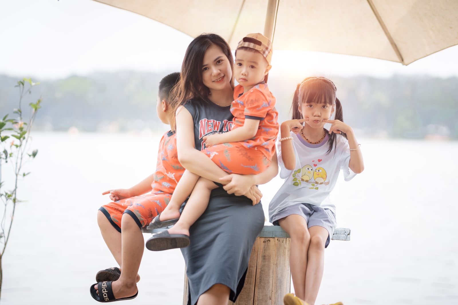 A mother sitting with her children under a sun umbrella